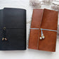 Black and brown leather refillable journals with beaded closures, next to dried flowers