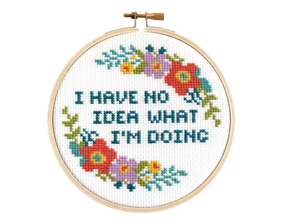 Finished cross stitch reading "I have no idea what I'm doing" in teal with coral and purple flowers in a wooden hoop