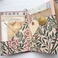 Open journal folio with a pink floral pocket, vintage book pages, a tag and a gold button