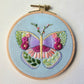 Close-up of the finished butterfly sampler embroidery in a wooden hoop