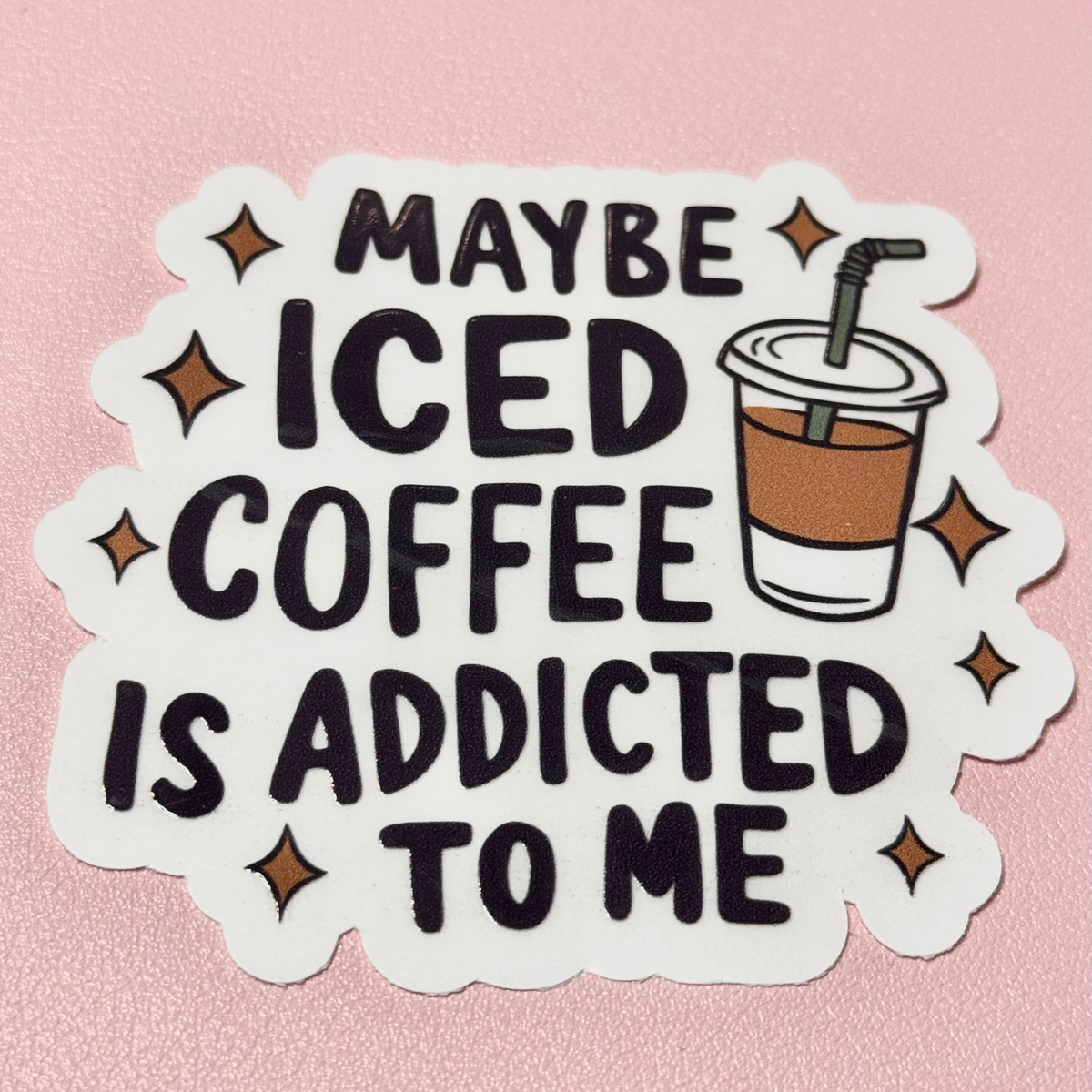 Die-cut sticker reading "Maybe iced coffee is addicted to me" with an iced coffee cup and sparkles