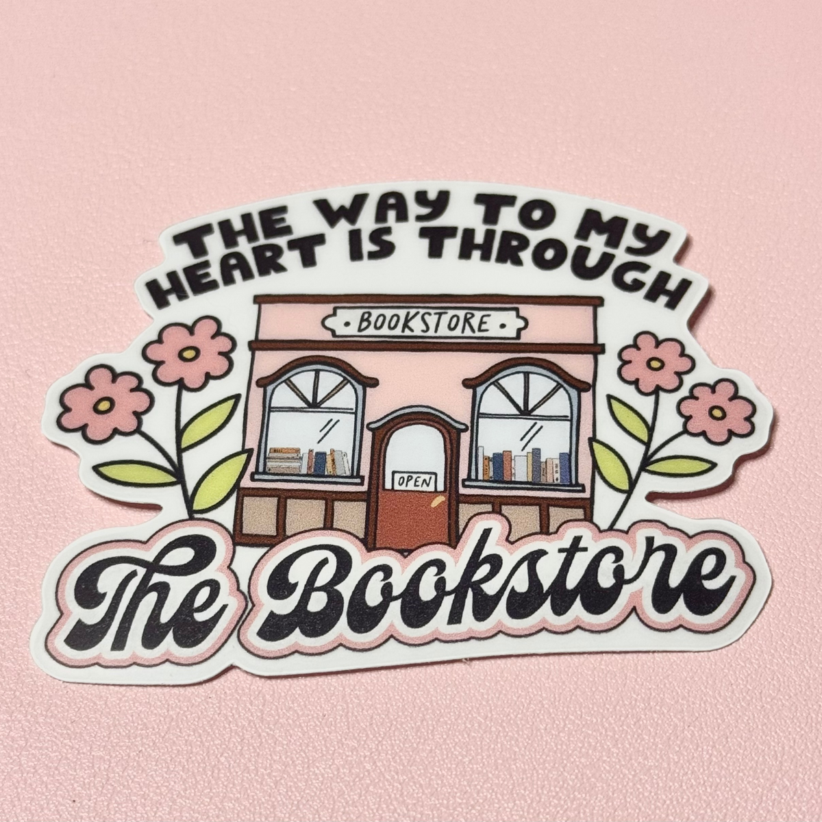 Sticker reading "The way to my heart is through the bookstore" with a pink bookshop front and flowers