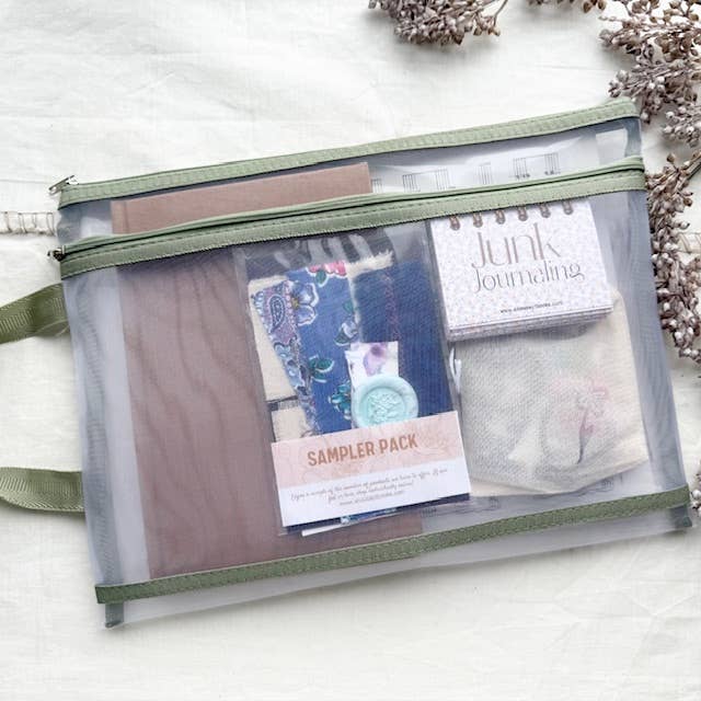 Junk journal kit packed in a green-trimmed zippered mesh pouch with journal, sampler pack and mini notebook