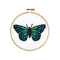 Finished butterfly cross stitch in teal, green and blue on white fabric in a wooden hoop
