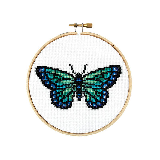 Finished butterfly cross stitch in teal, green and blue on white fabric in a wooden hoop
