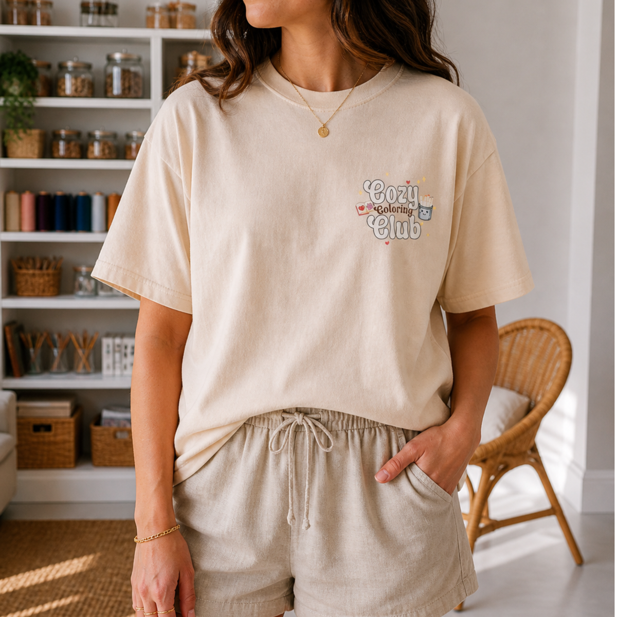 Model wearing a cream T-shirt with a small Cozy Coloring Club print on the front