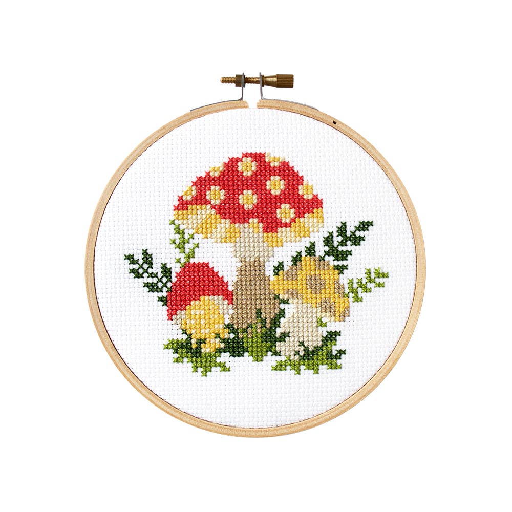 Finished mushroom cross stitch with red and yellow toadstools and ferns in a wooden hoop