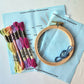 Kit contents: pre-printed light blue fabric, embroidery hoop, DMC floss in six colors and needles