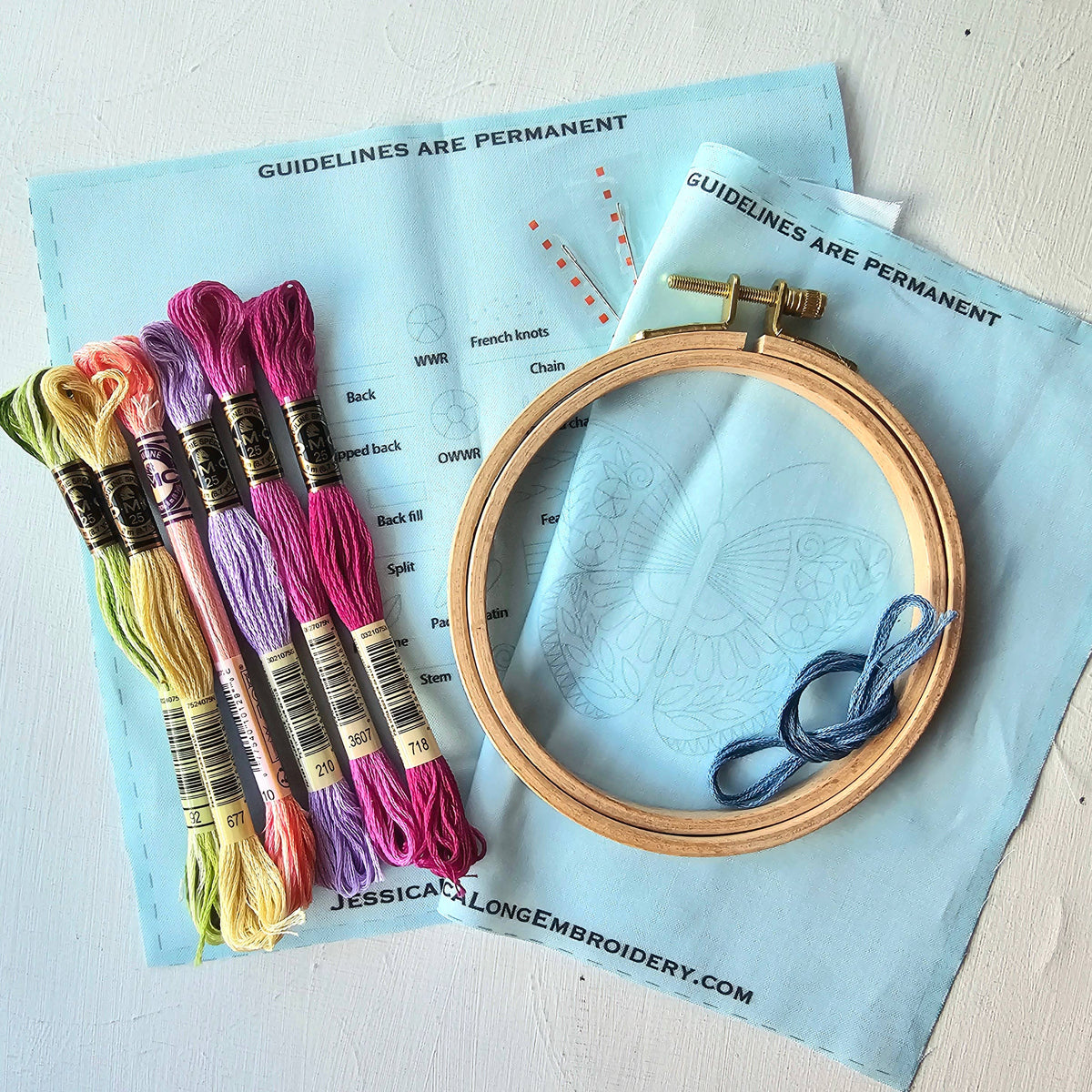 Kit contents: pre-printed light blue fabric, embroidery hoop, DMC floss in six colors and needles