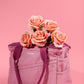 Dusty pink Soolla craft bag filled with peach roses on a pink background
