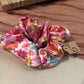 Pink satin scrunchie with a retro orange, pink and gold flower print and a $5 price tag