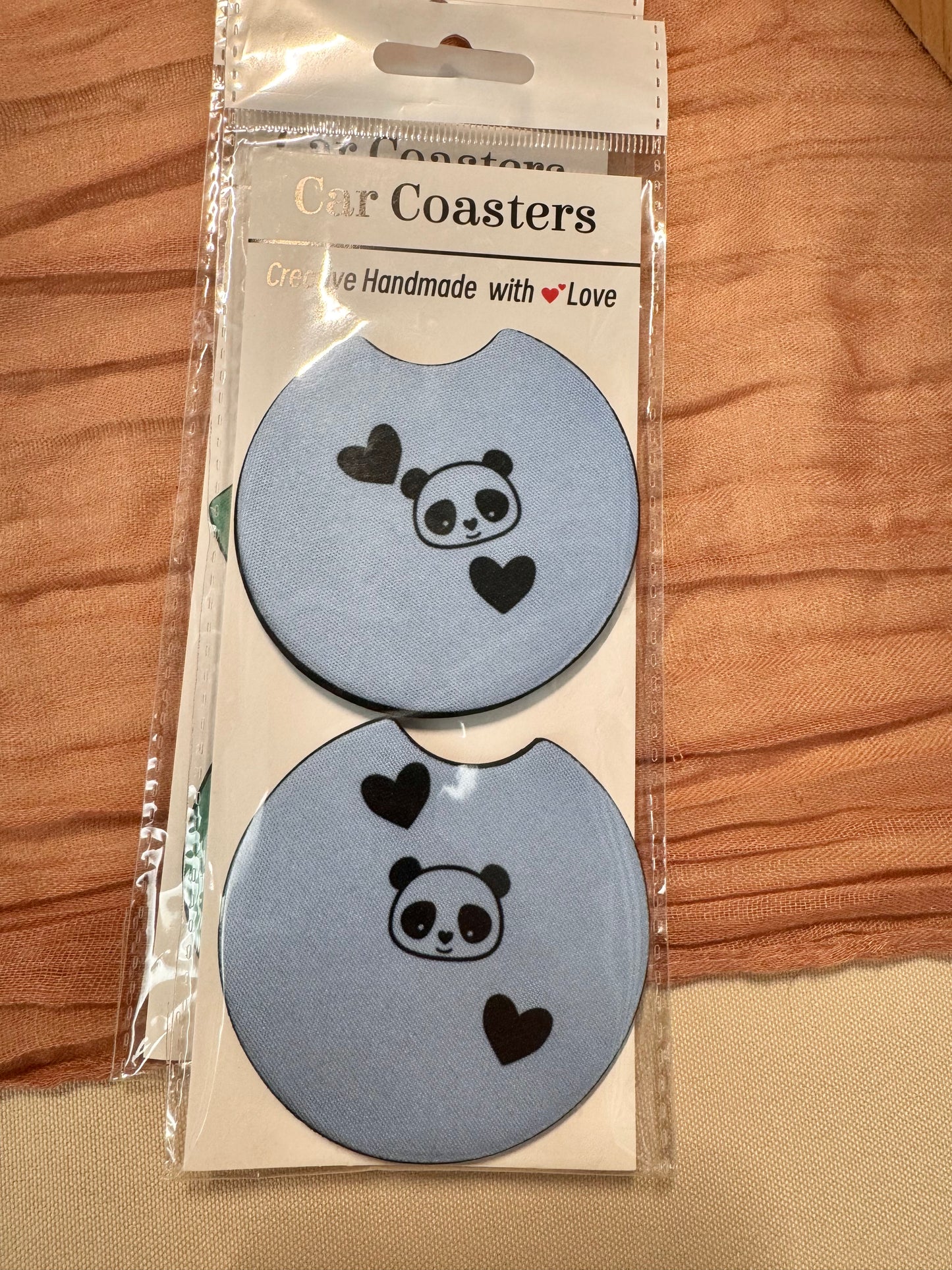 Pair of light blue car coasters with a small panda face and black hearts