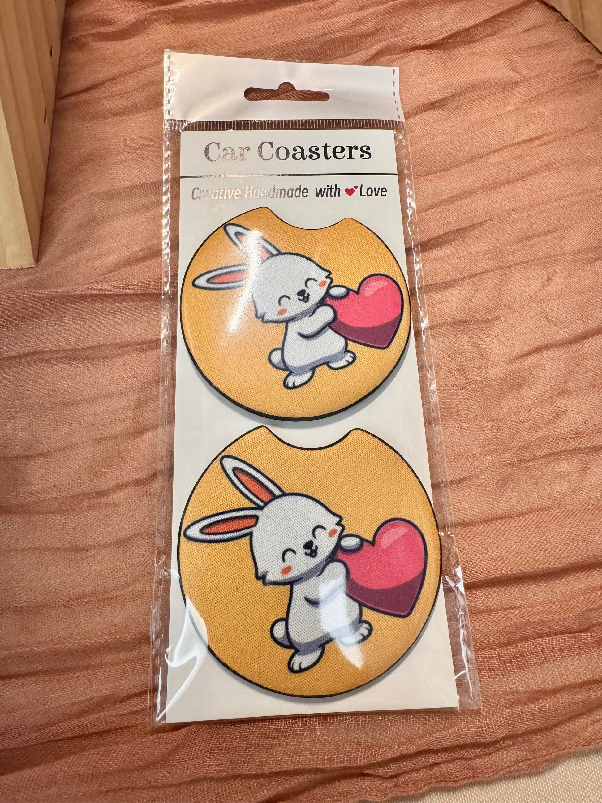 Pair of orange car coasters with a white bunny hugging a red heart