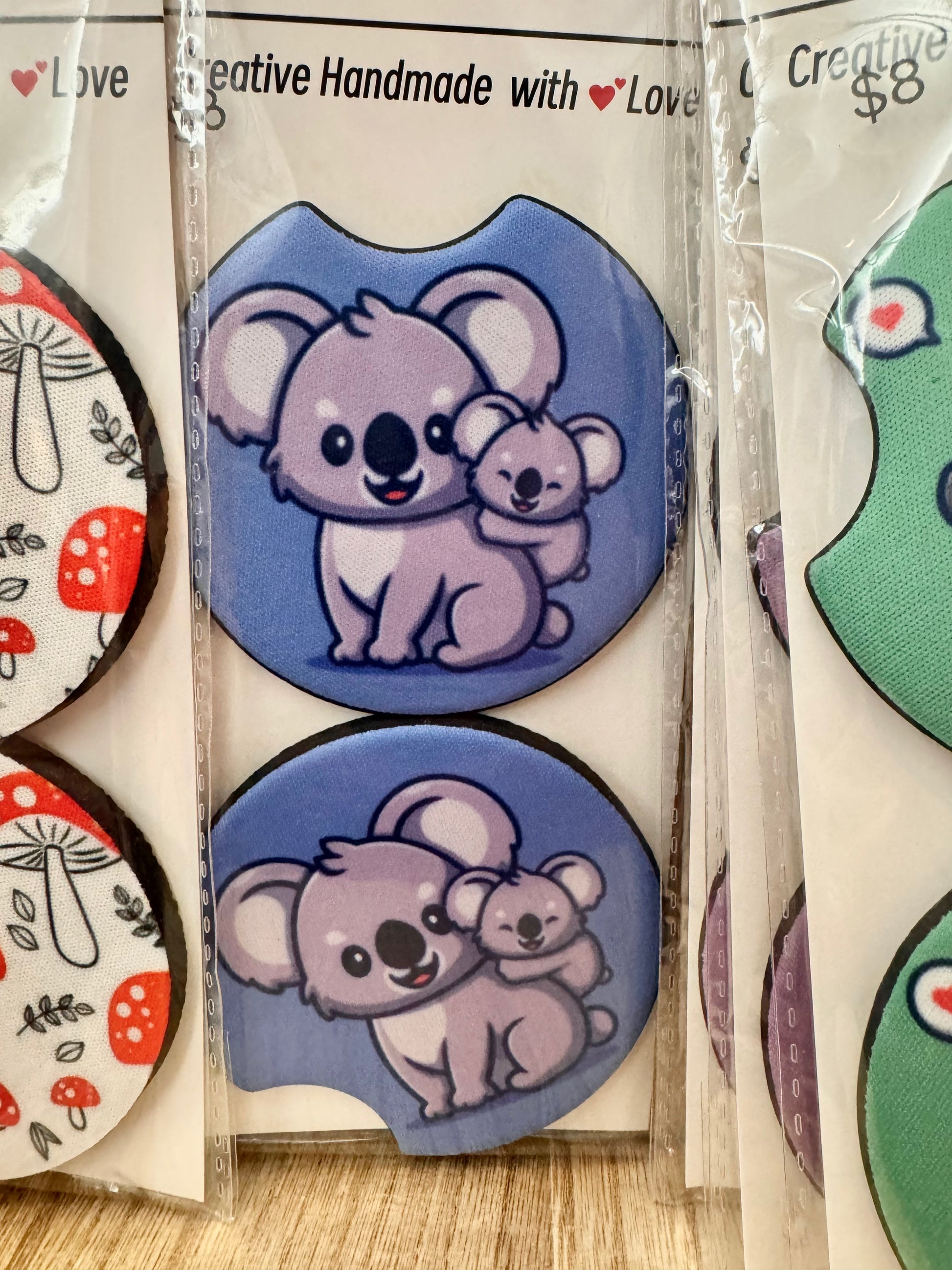 Pair of car coasters with a cartoon mother and baby koala on blue