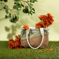 Sage and brown Soolla craft bag with orange chrysanthemums on grass under eucalyptus branches