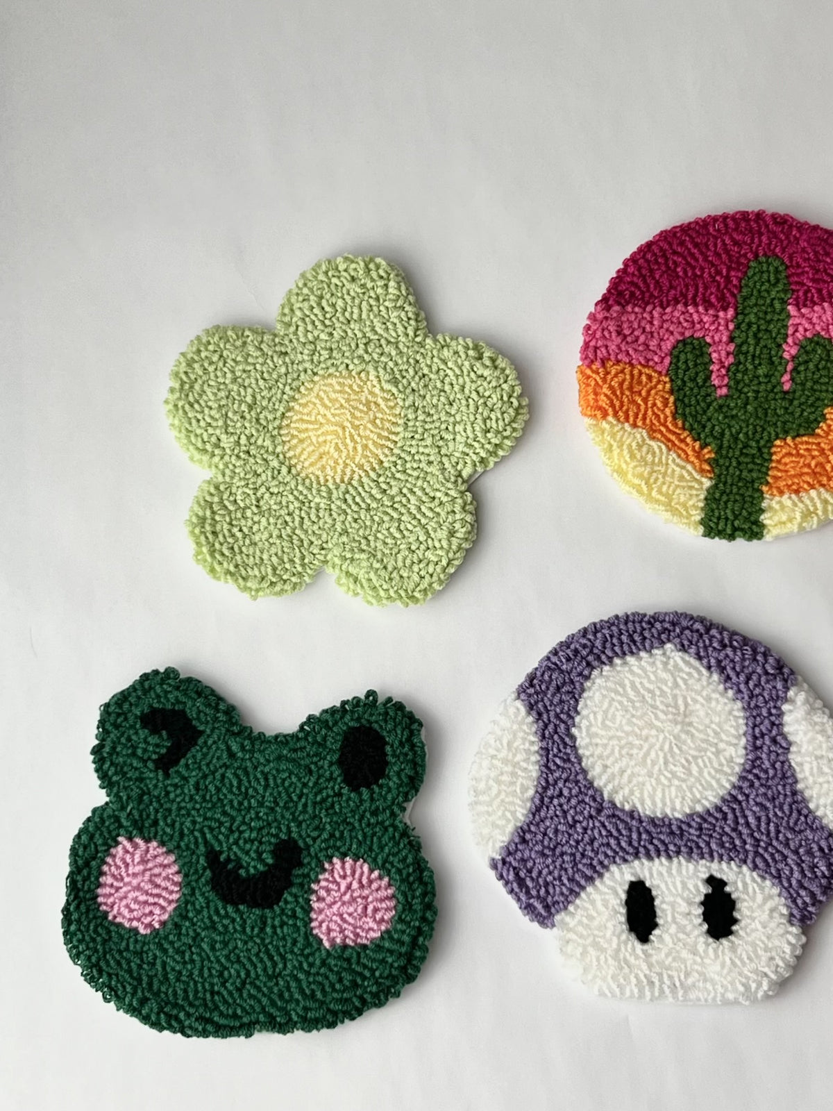 Punch needle coasters: green daisy, cactus sunset, green frog face and purple mushroom