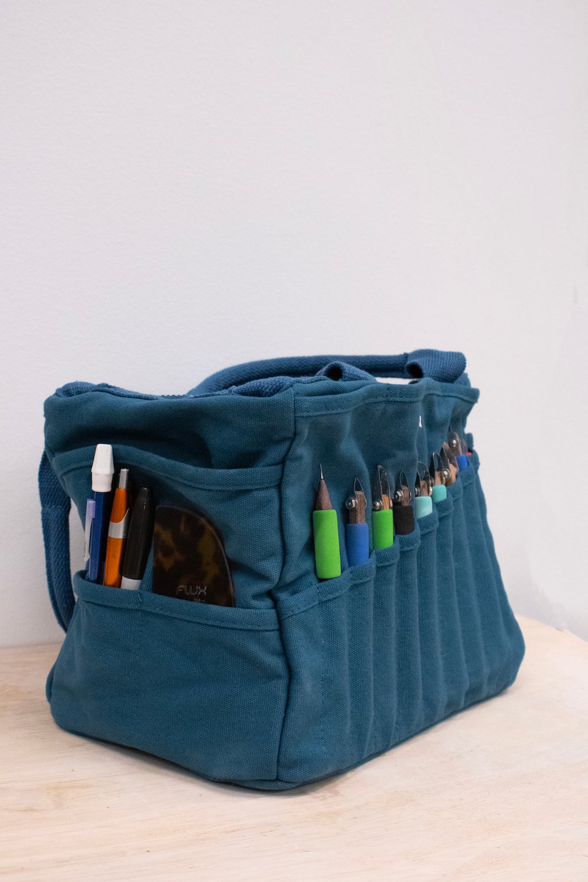 Side view of the bag with pens and tools in its outer pockets