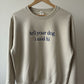 Sand "tell your dog i said hi" crewneck with navy embroidery on a wooden hanger