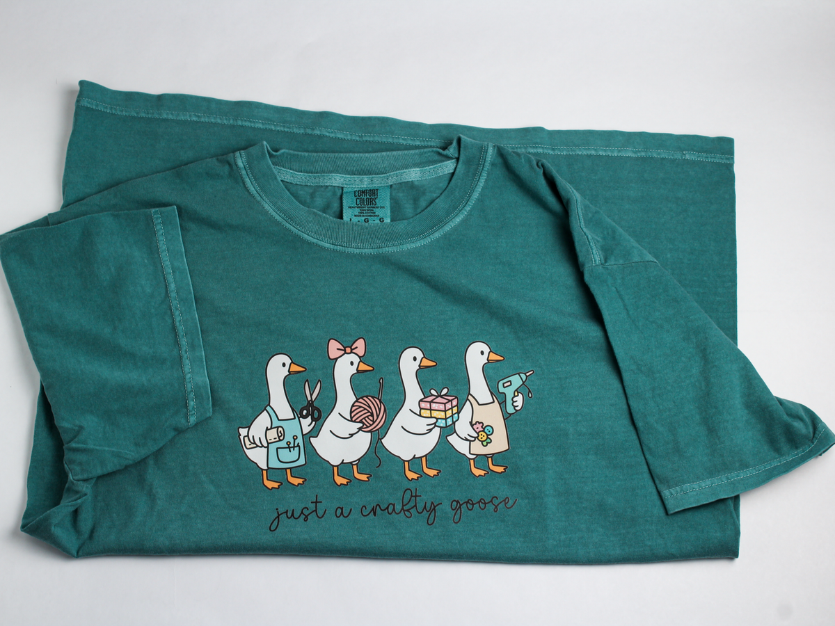Teal "just a crafty goose" T-shirt laid flat