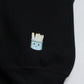 Close-up of the smiling marker-cup design on the black crewneck's sleeve