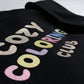 Angled close-up of the pastel Cozy Coloring Club embroidery on a black crewneck