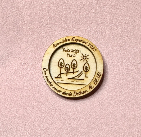 Round engraved wood token with trees, a sun and "Asamblea Especial 2025, Adoración Pura"