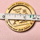 Engraved wood token held against a measuring tape to show its size