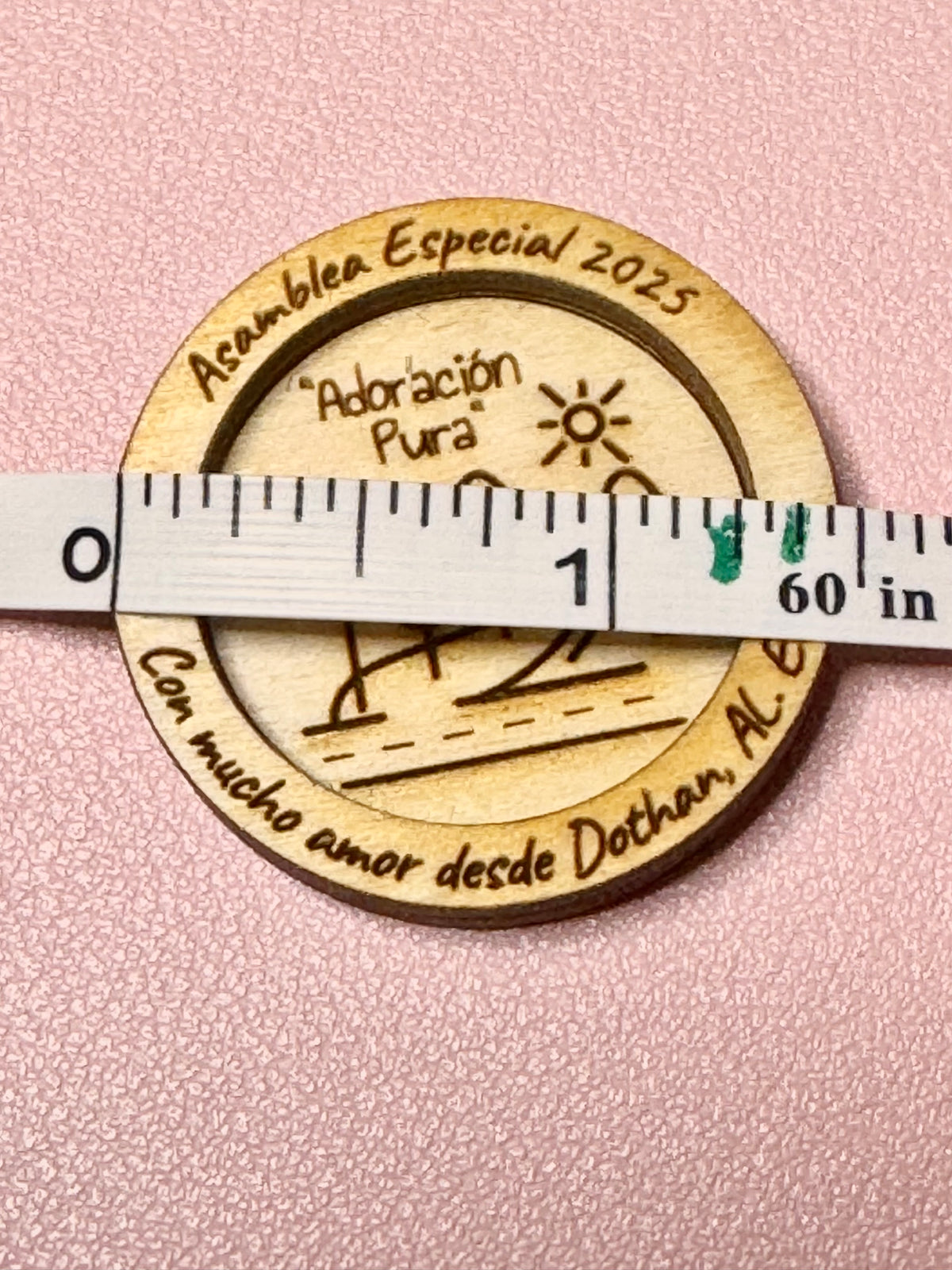 Engraved wood token held against a measuring tape to show its size