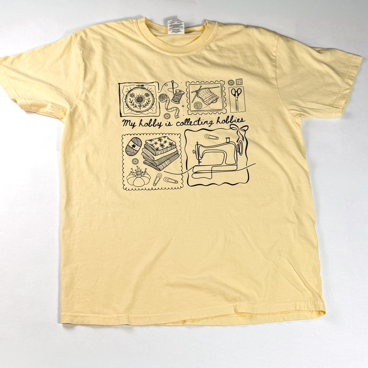 Butter yellow "My hobby is collecting hobbies" T-shirt laid flat