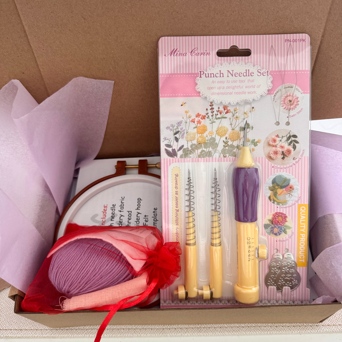 Punch needle kit box with a Mina Carin punch needle set, embroidery hoop, lavender yarn and instructions