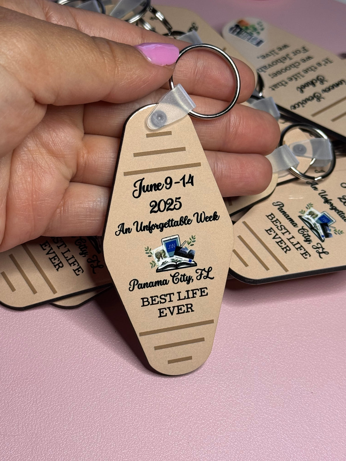 Hand holding a tan motel-style keychain reading "June 9-14 2025, An Unforgettable Week, Panama City, FL, Best Life Ever"