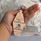 Hand holding a pink motel-style keychain reading "Junio 23-28 2025, Una Semana Memorable, No hay vida mejor"