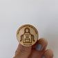 Hand holding an engraved wood token with an apron and "Equipo de Cocina 2025"