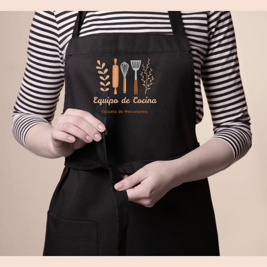 Model wearing a black apron printed with kitchen utensils and "Equipo de Cocina"