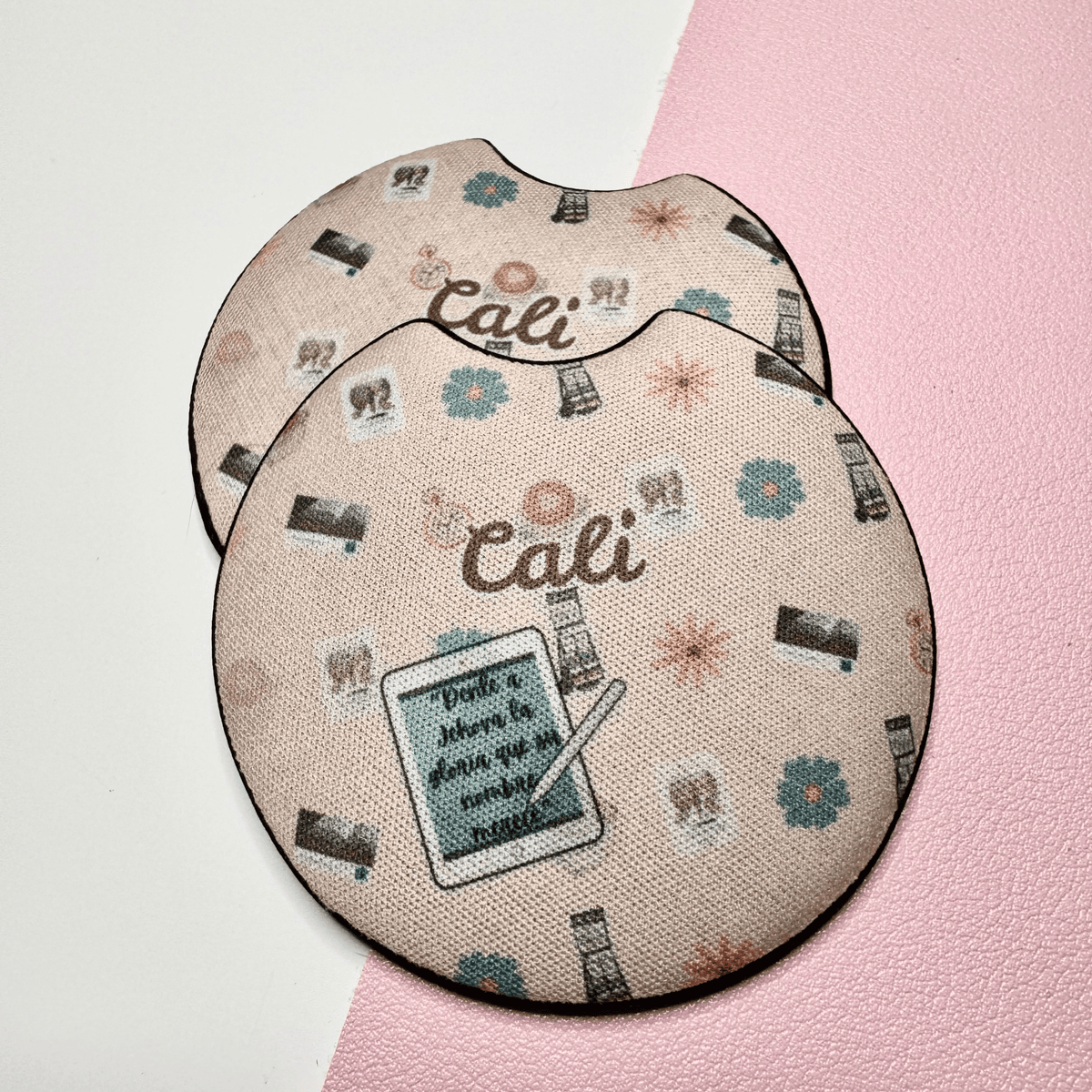 Pair of pink car coasters personalized with the name Cali and small illustrated icons