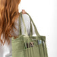Model carrying the green Soolla craft bag on the shoulder, with pens and scissors in the front pockets