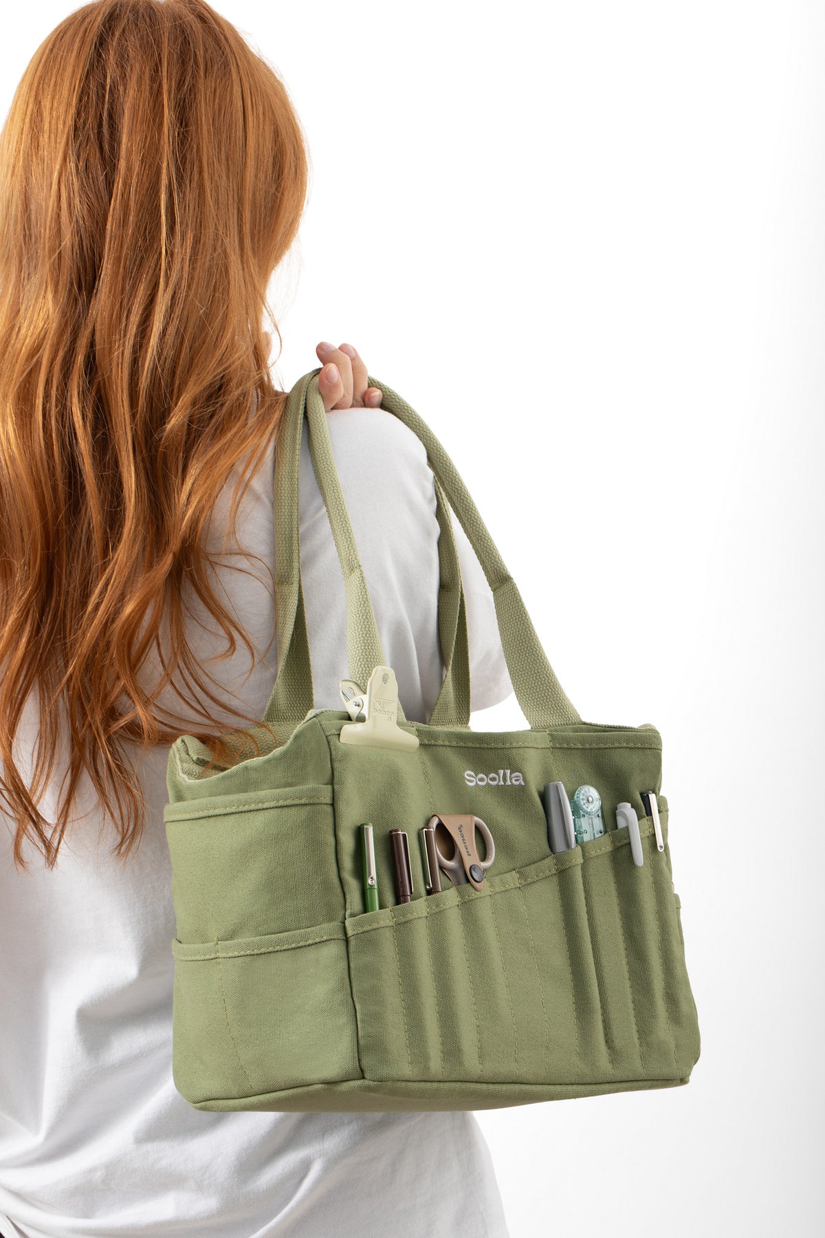 Model carrying the green Soolla craft bag on the shoulder, with pens and scissors in the front pockets