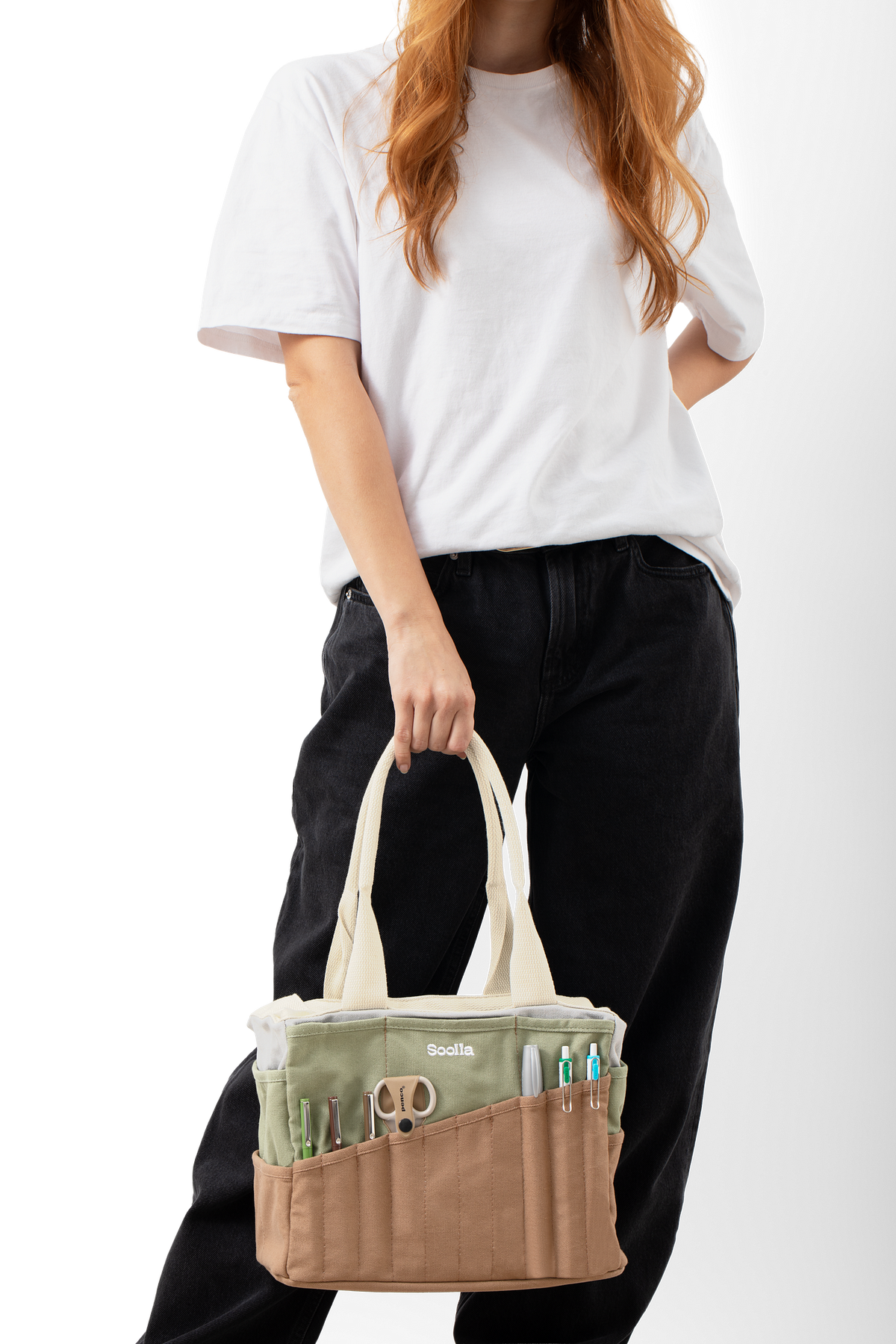 Model holding the sage and brown Soolla craft bag with scissors and pens in the front pockets