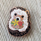 Close-up of the enamel hedgehog needle minder holding a flower bouquet