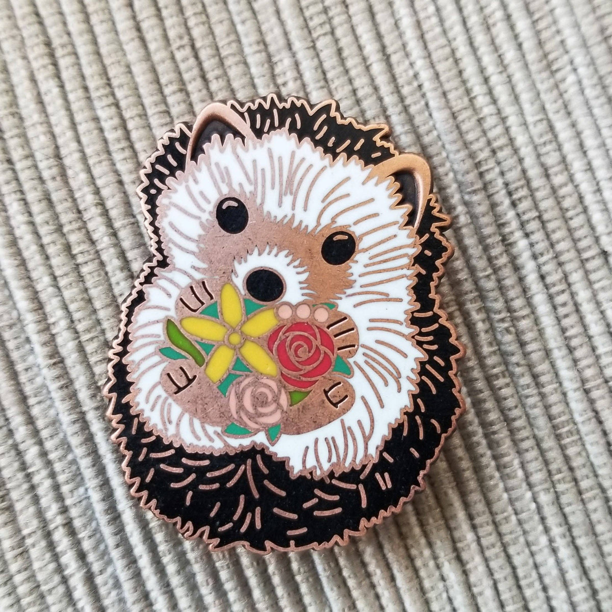 Close-up of the enamel hedgehog needle minder holding a flower bouquet