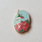 Angled view of the hummingbird and pink hibiscus enamel needle minder