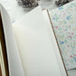 Open blank mixed media insert beside a pastel floral cover