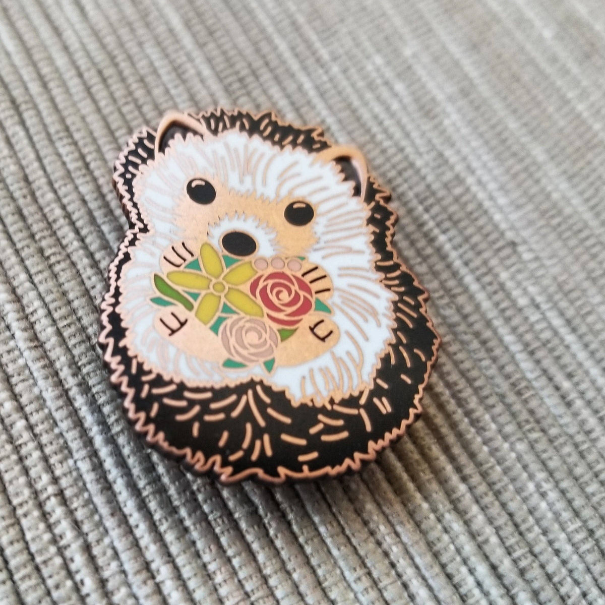 Angled close-up of the hedgehog enamel needle minder with its rose gold outline