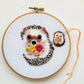 Embroidered hedgehog with a flower bouquet in a hoop, with the matching needle minder
