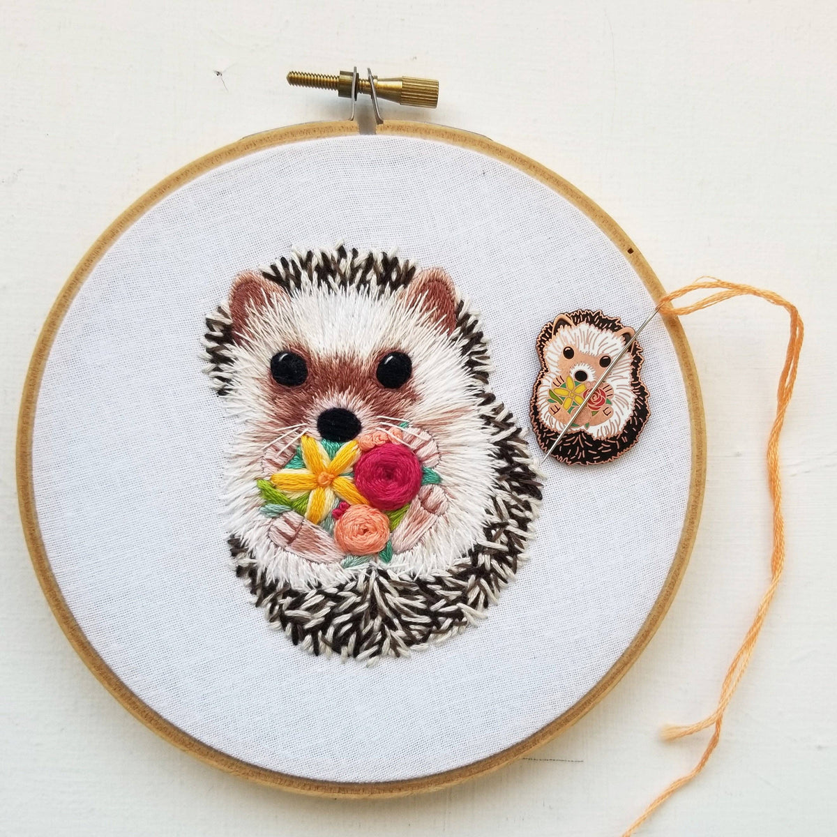 Embroidered hedgehog with a flower bouquet in a hoop, with the matching needle minder