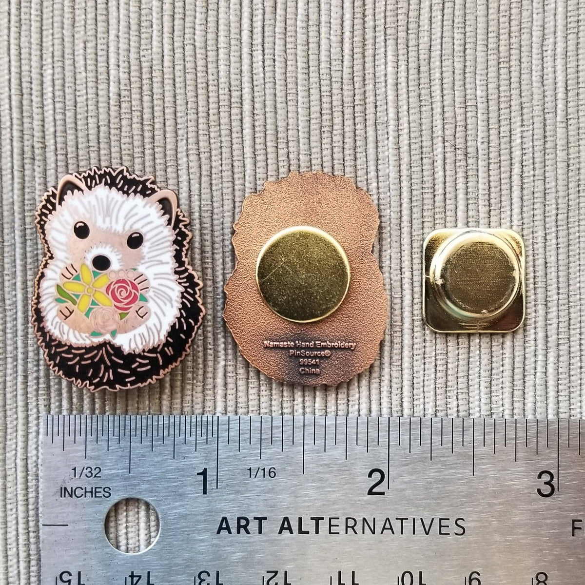 Front and back of the hedgehog needle minder and its magnet, shown against a ruler for size
