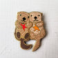 Enamel needle minder of two sea otters holding hands with red and orange starfish